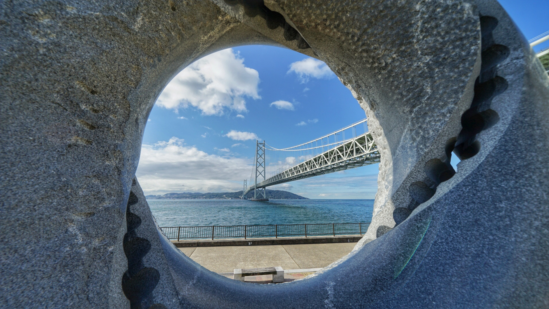 水辺に橋がかかっている風景を丸い穴から除いている写真